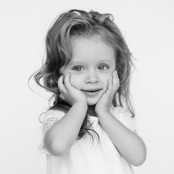 little girl with messy hair touching her face